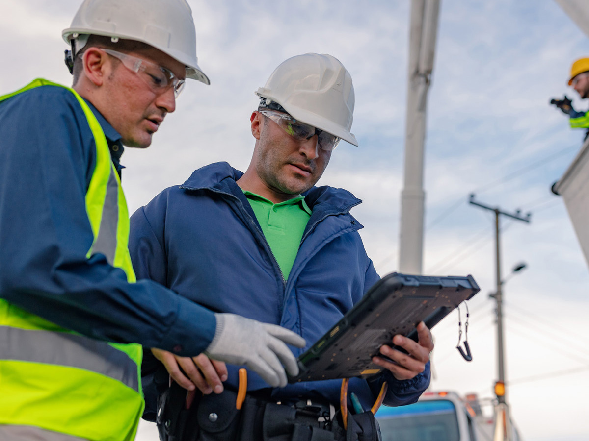 Two electrical utility workers looking at a Zebra Tablet