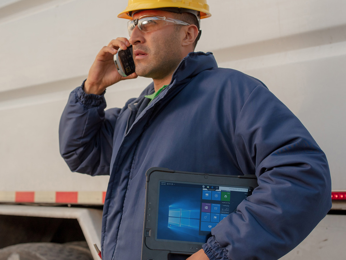 Utilities Worker speaking on a zebra mobile device while holding a zebra tablet