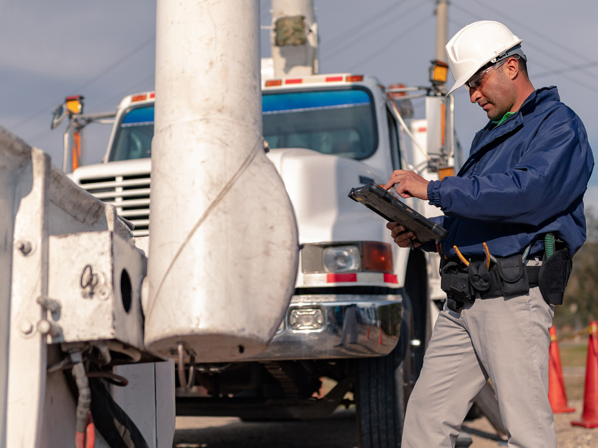 Electrical Utilities Worker using a Zebra Tablet with truck in the background