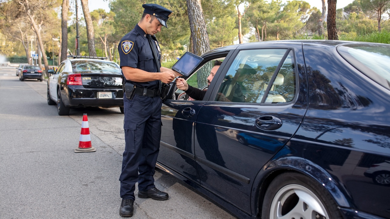 A civilian in a car hands their driver’s license to a police officer equipped with a Zebra ET8x device