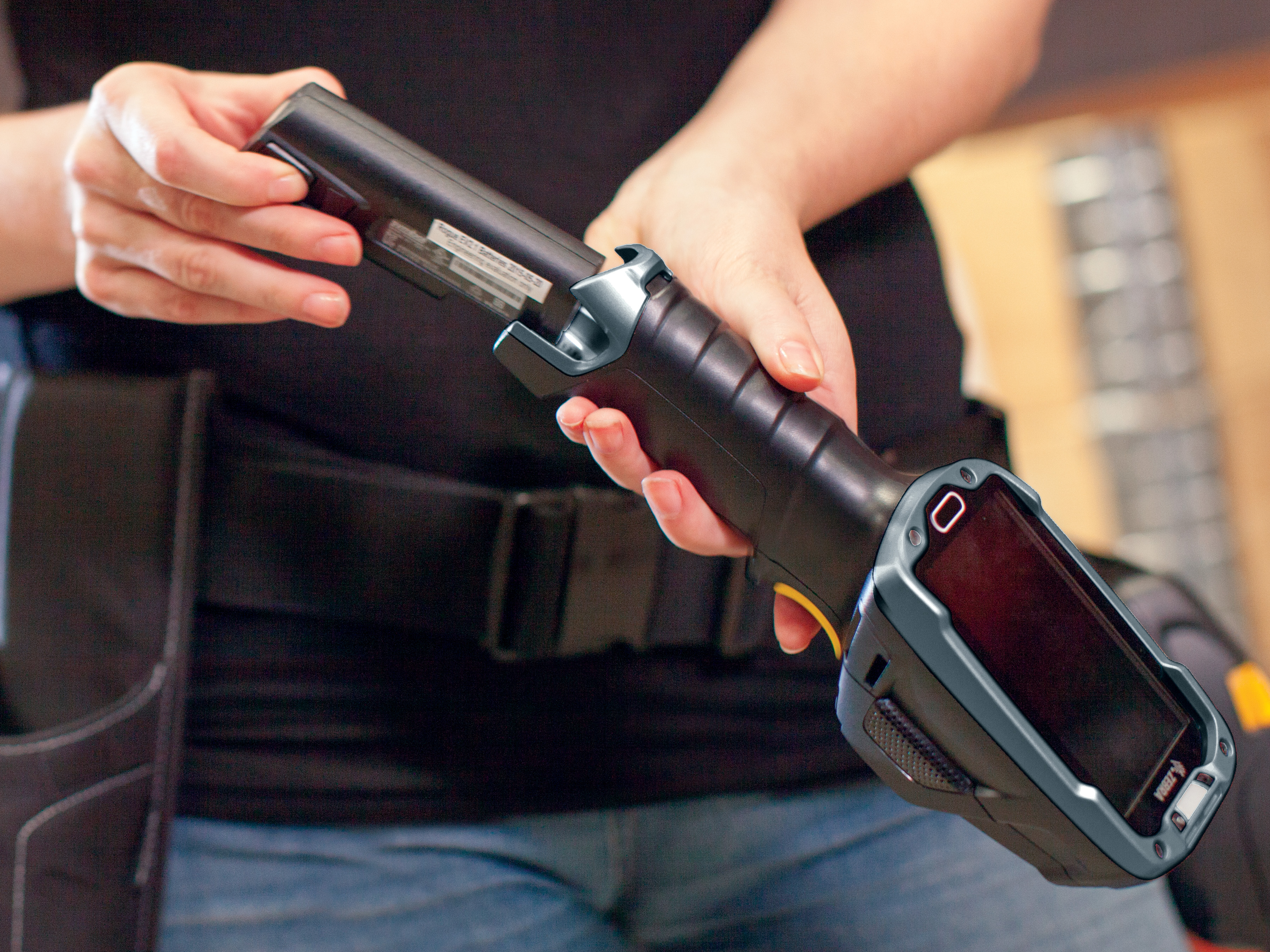 A person is inserting a battery into a Zebra device.