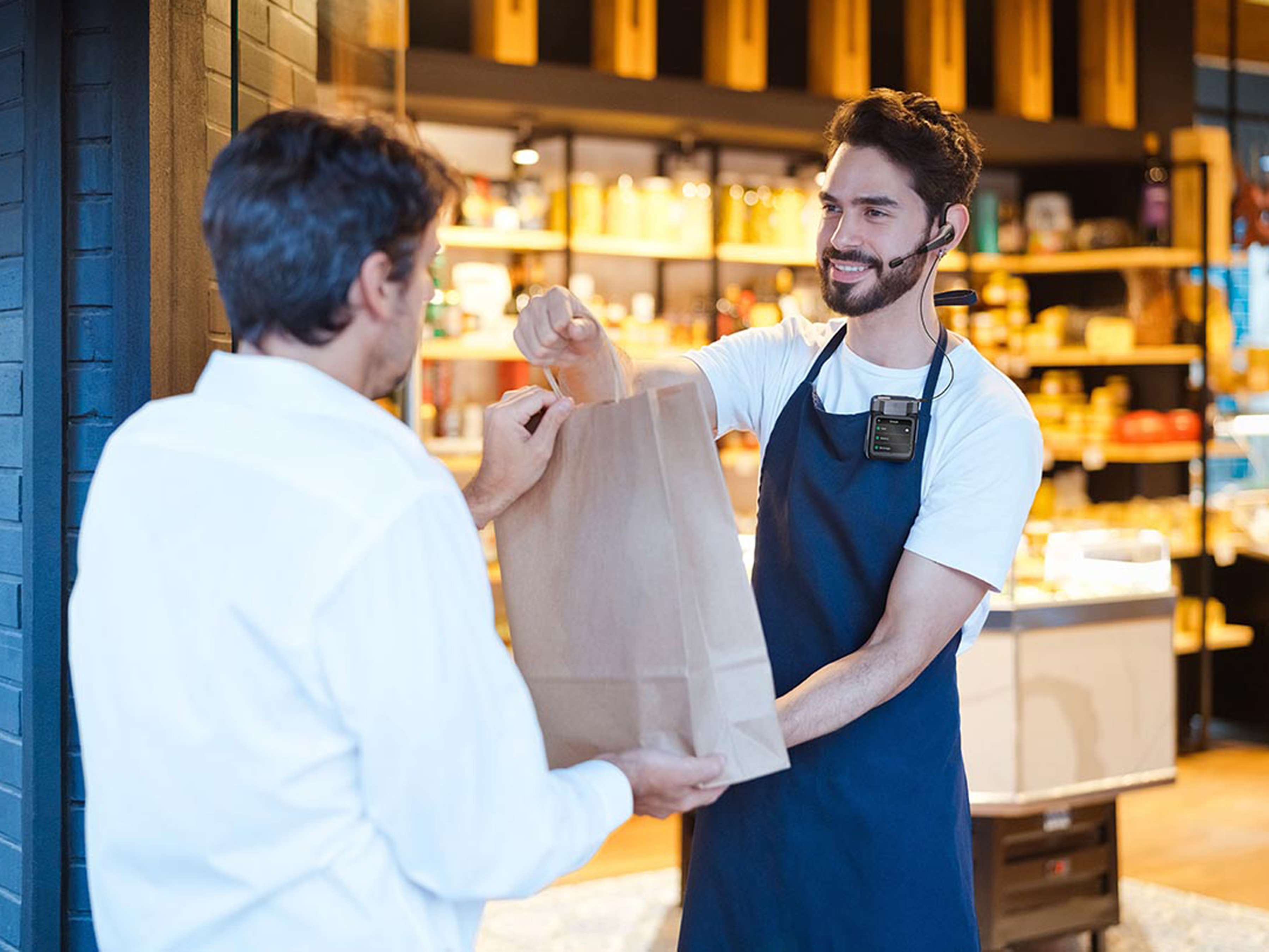 In a modern retail environment, a salesperson uses a headset to efficiently deliver a package to a customer completing a store pickup.