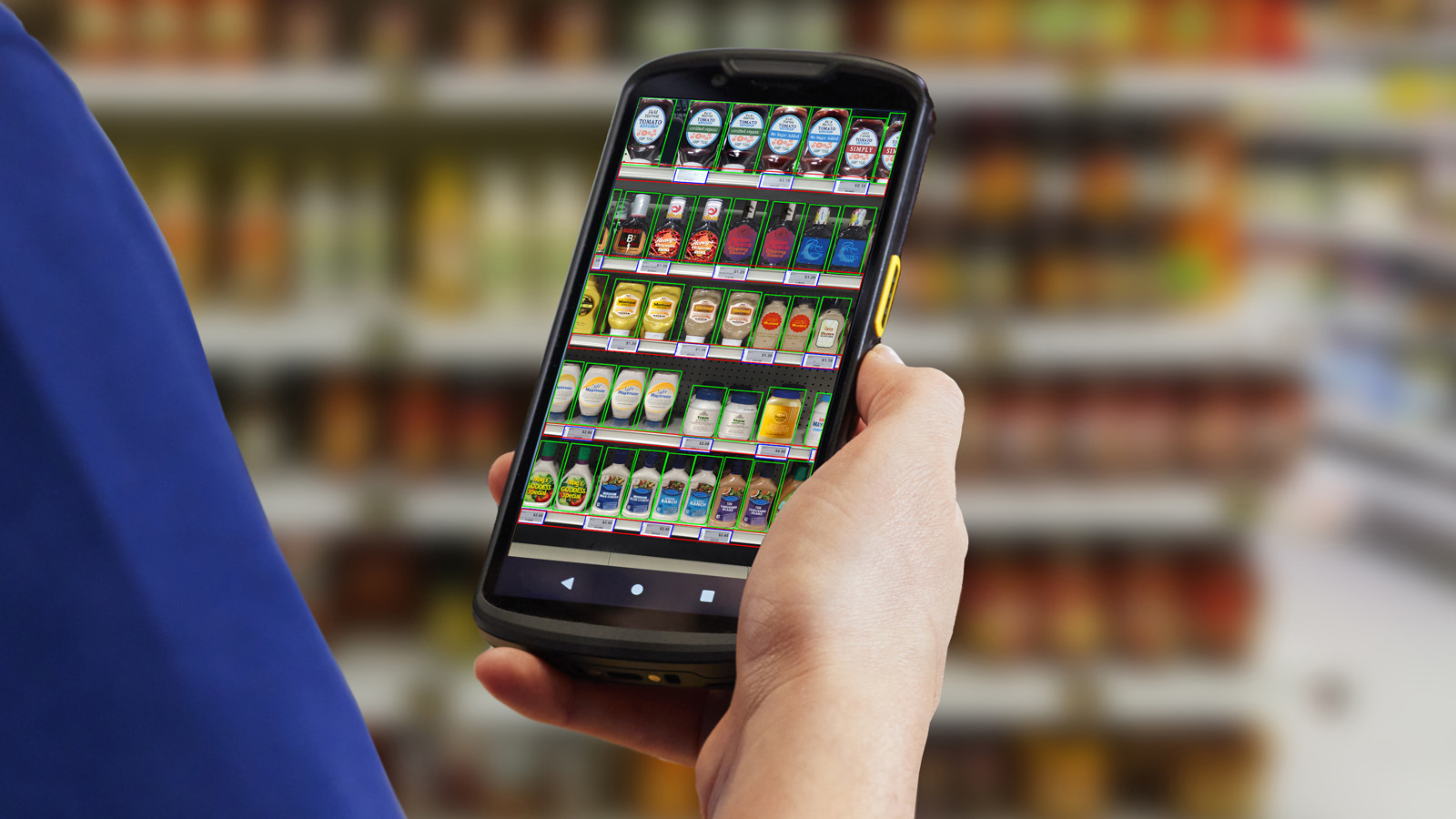 An employee in a market is looking through a Zebra mobile computer, using the Zebra mobile computing AI suite to locate a product on a shelf
