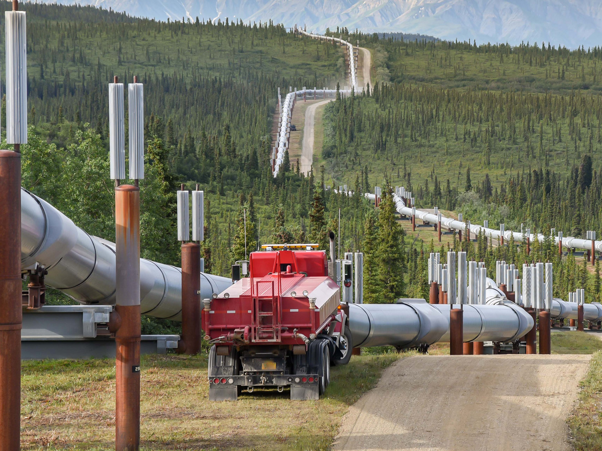 Red truck parked by pipelines in a remote setting