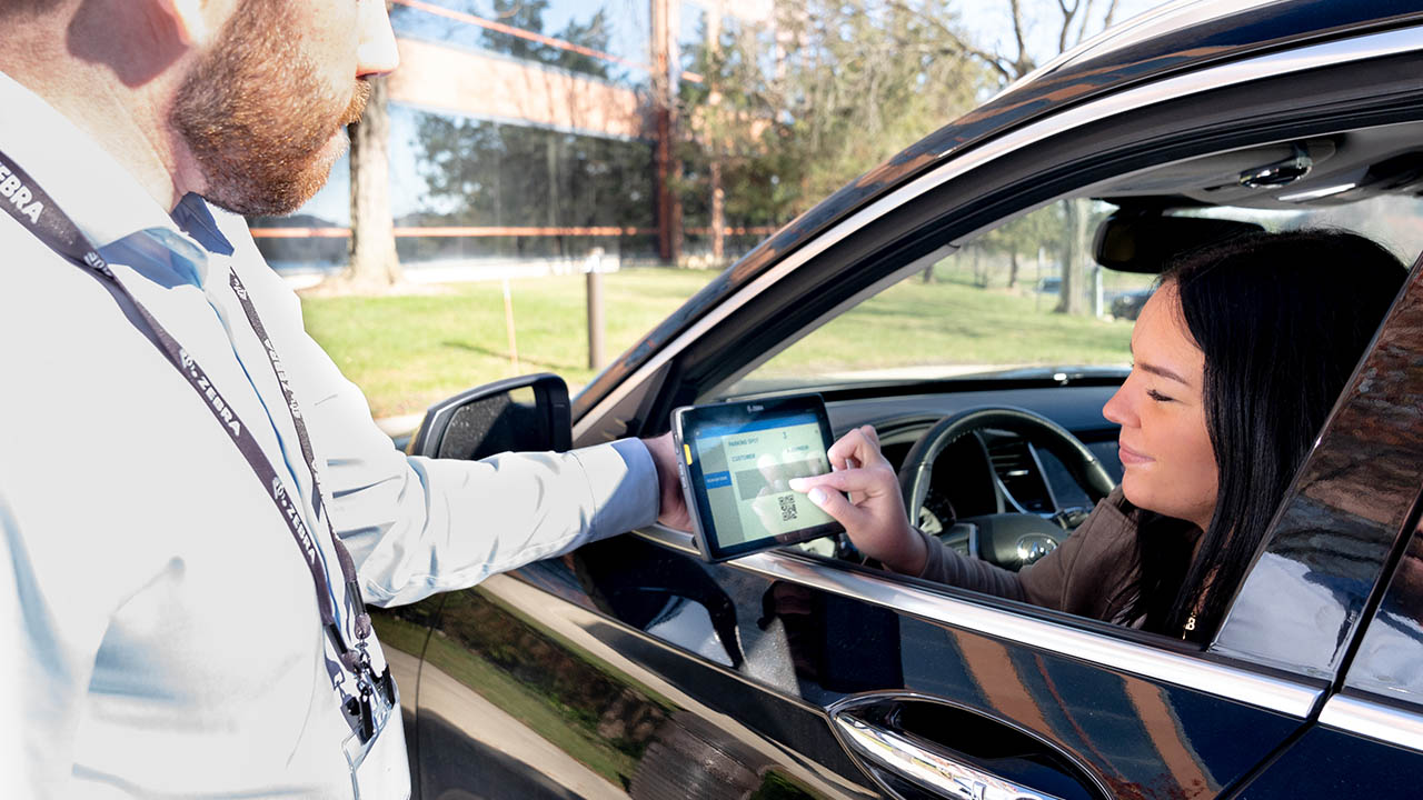 A woman signs for a curbside pickup order on a Zebra tablet