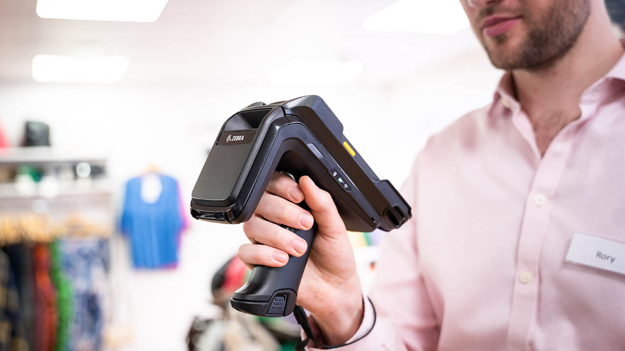 A retail store associate looks at data on a mobile computer equipped with an RFID sled