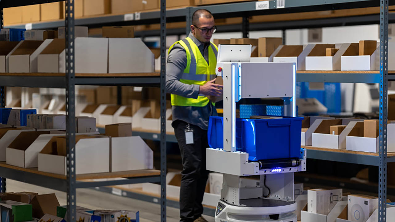 A warehouse worker interacts with a Fetch autonomous mobile robot from Zebra