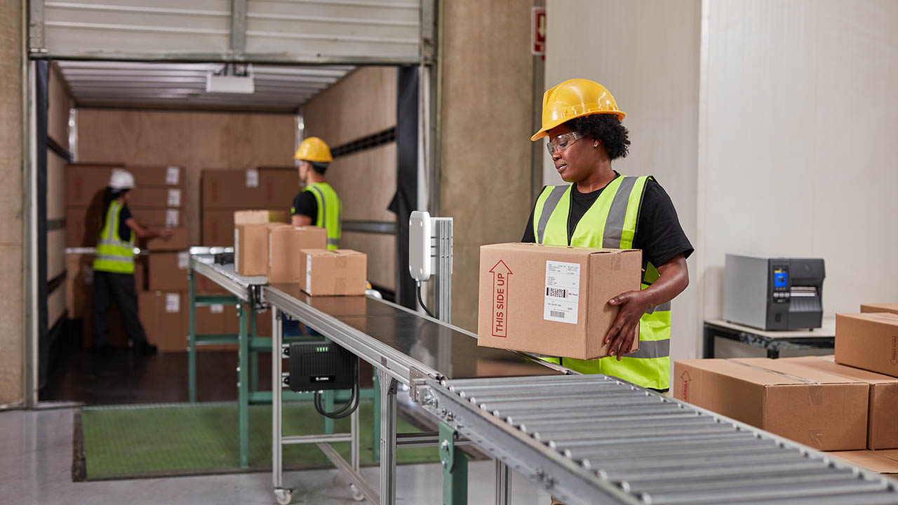 Warehouse workers unload packages from a truck using a receiving line