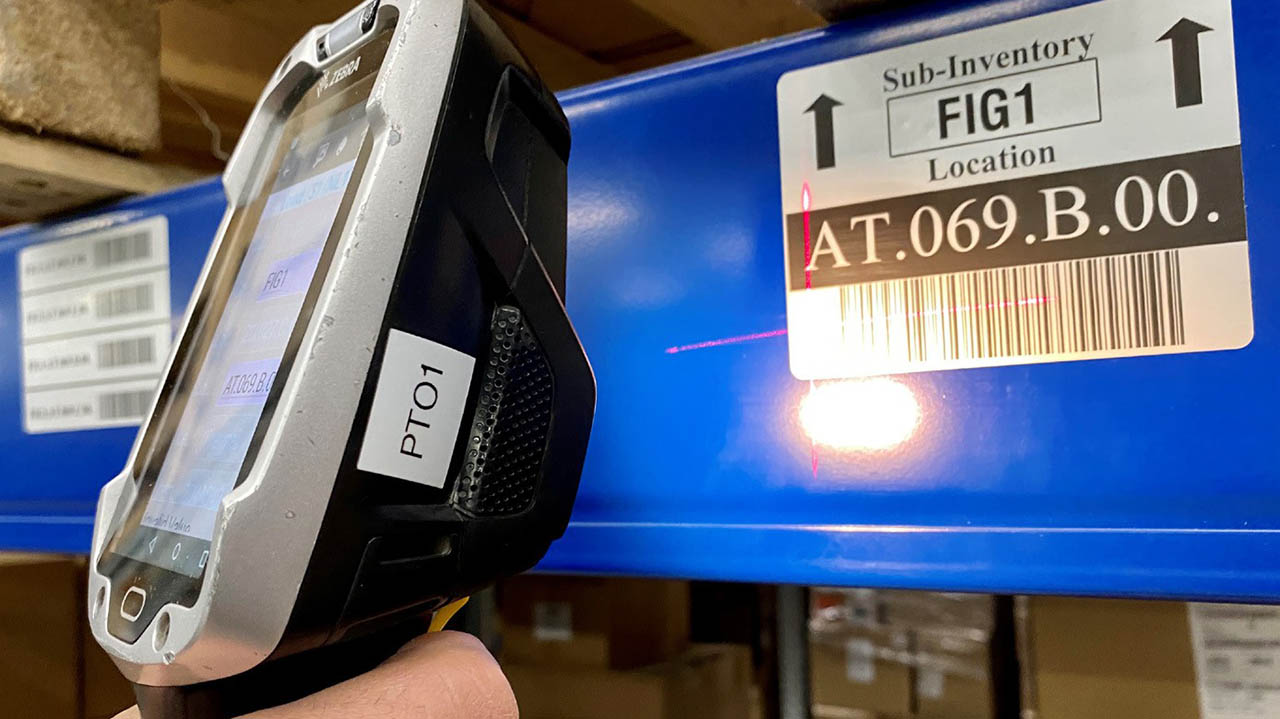A Zebra mobile computer is used to read a barcode label on a warehouse stock item.