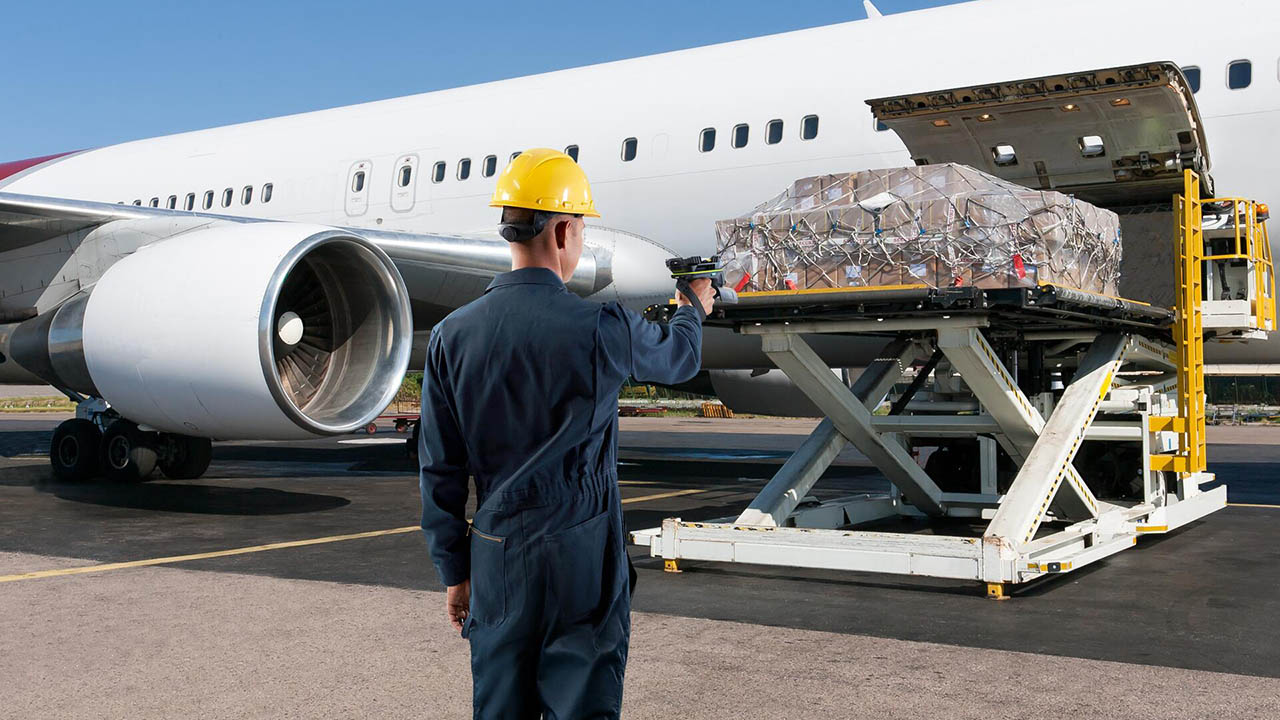 An airline worker uses a mobile computer on the tarmac to track inventory being loaded into a plane's cargo hold.