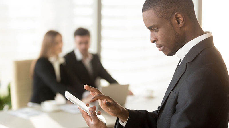 A banker sends a message on his personal smartphone while meeting with clients