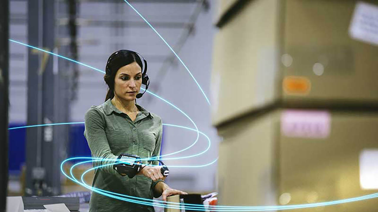 A warehouse worker uses a ring scanner to scan boxes.