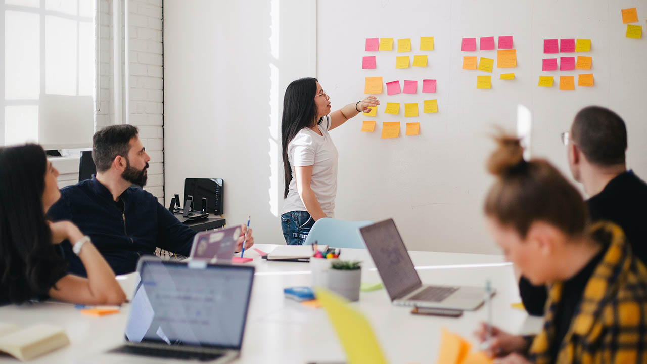 A woman leads a group discussion at a white board.