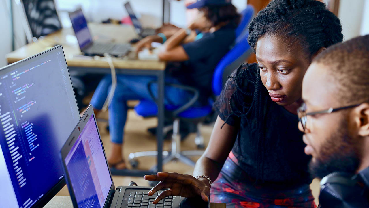 Two people look at a computer monitor