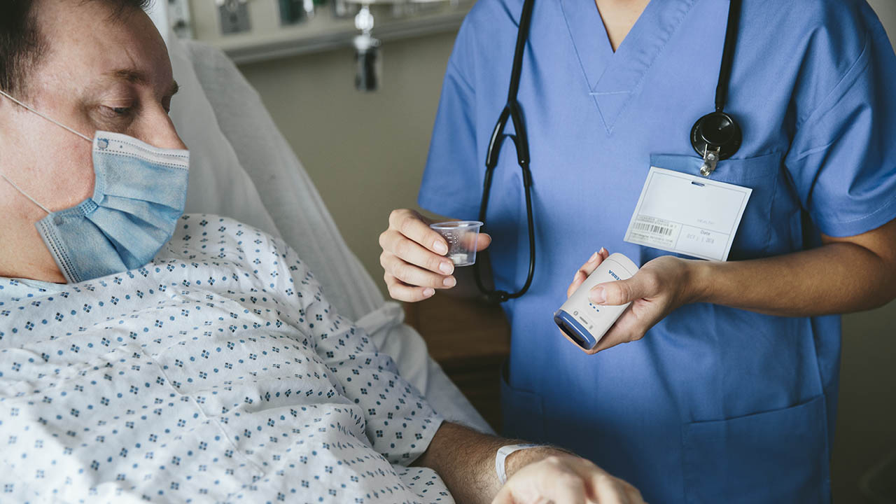 A nurse gives medication to a hospitalized patient 