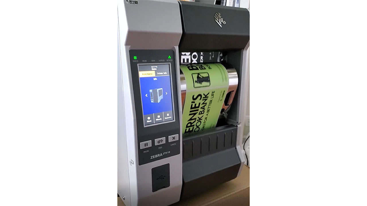 A green Bernie's Book Bank label is printed on a Zebra printer