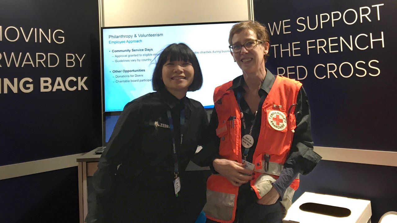 A Zebra employee and a French Red Cross volunteer collect donations at Zebra's 2020 EMEA Sales Kickoff