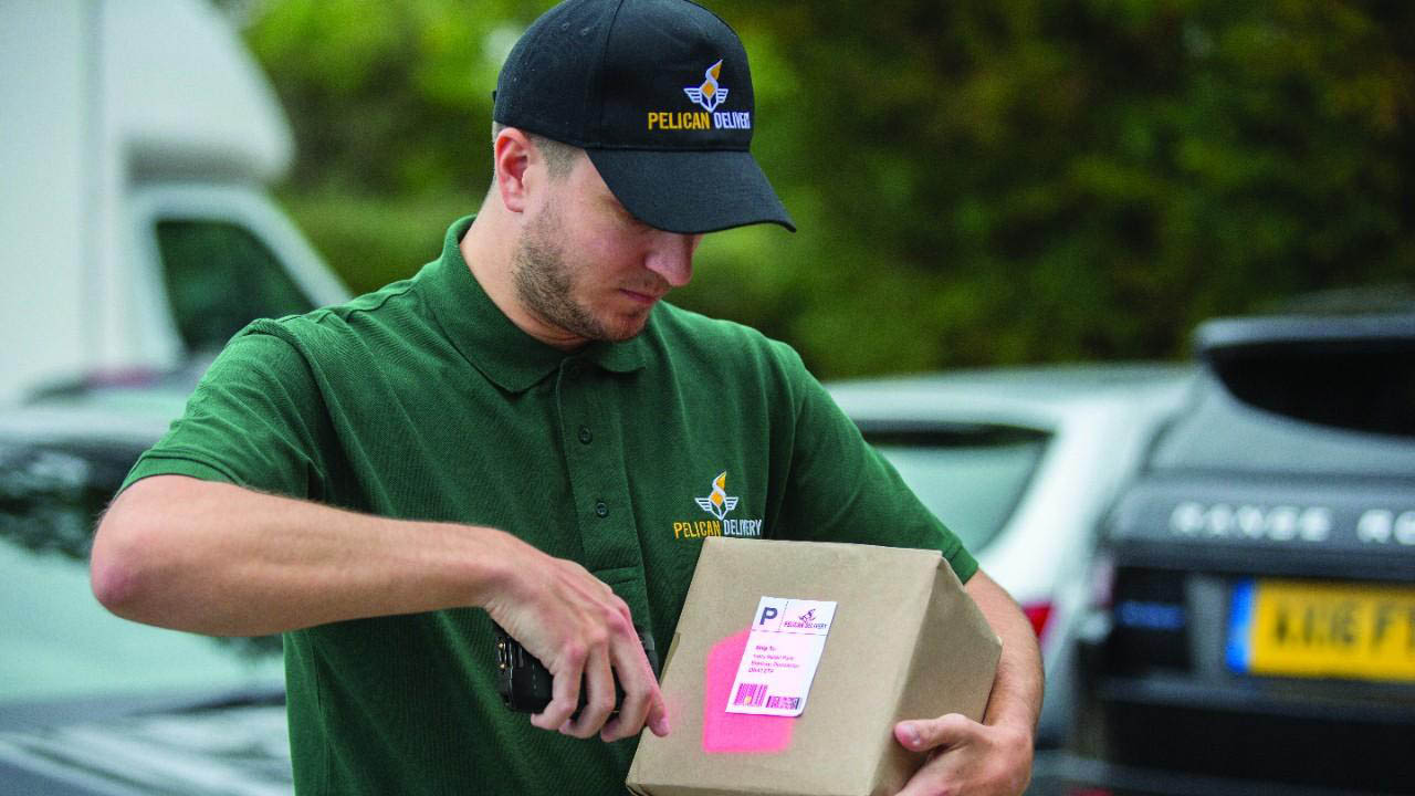 A delivery driver uses a TC26 mobile computer to scan a label on a package