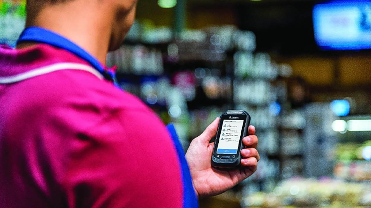 A grocery store associate looks at alerts on his enterprise-grade handheld mobile computer 