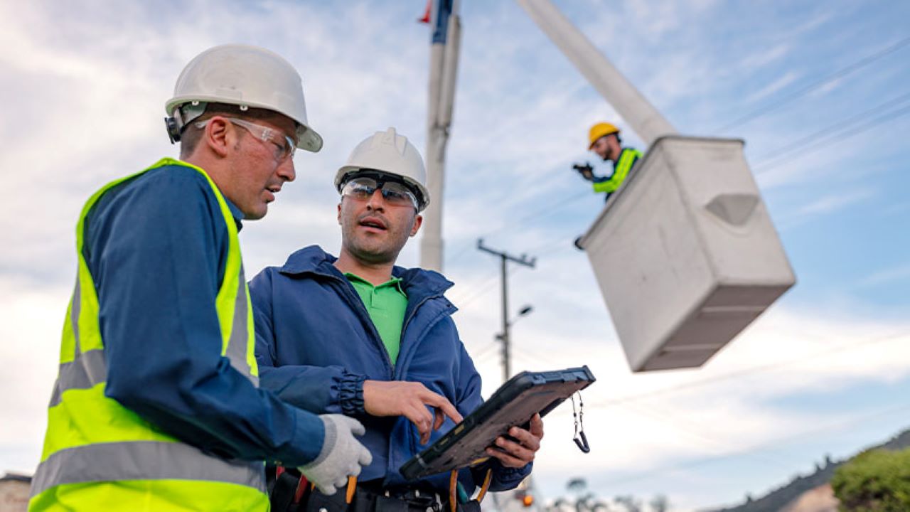 Two field workers review information on a rugged tablet