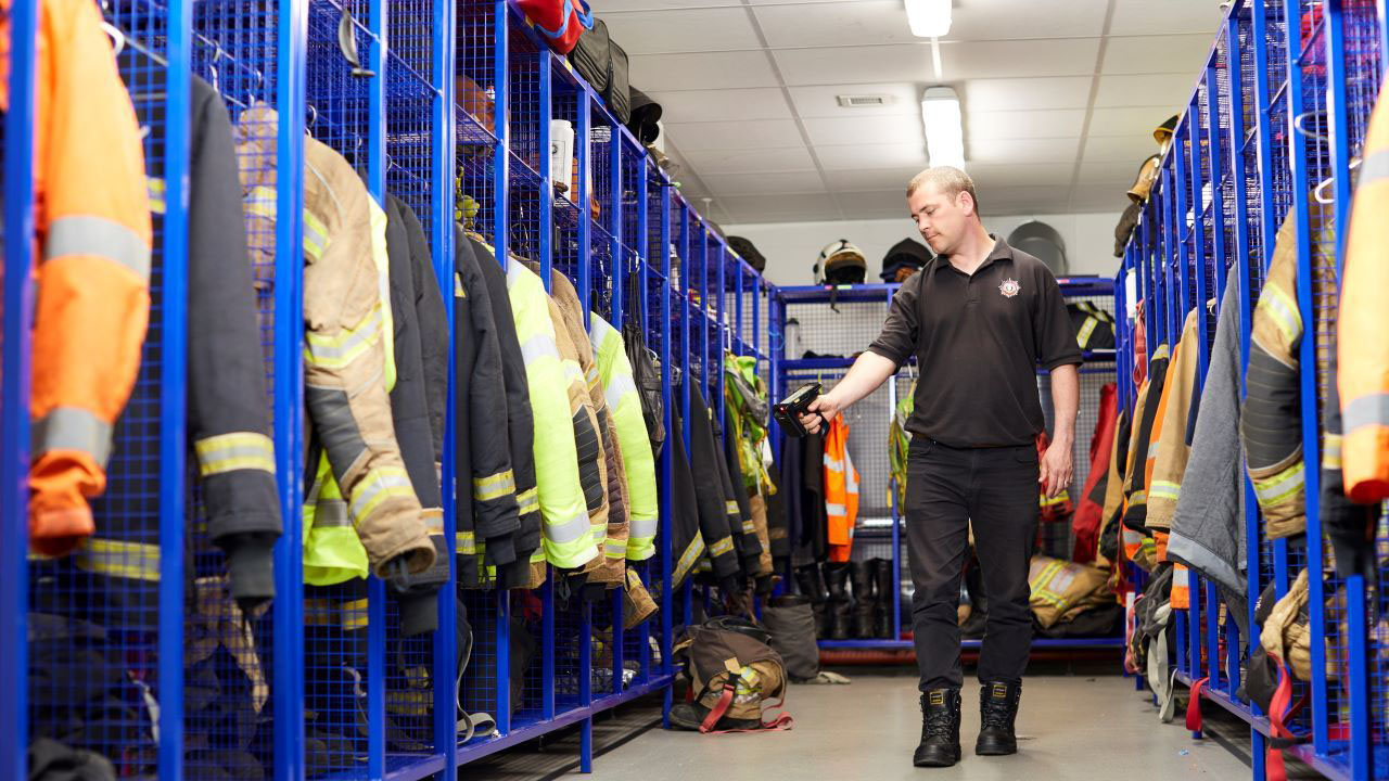 A firefighter uses a Zebra TC52 mobile computer with an RFID sled to scan inventory in a locker room