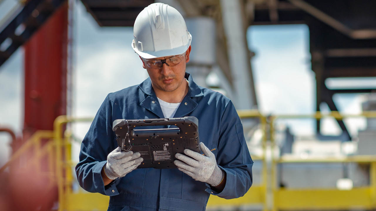 A utility worker looks at a rugged tablet screen