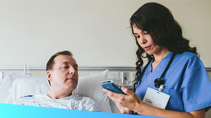 Female healthcare provider uses a handheld touch computer to provide bedside care to a patient