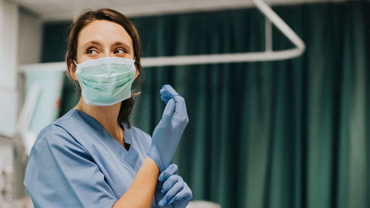 A nurse puts on gloves