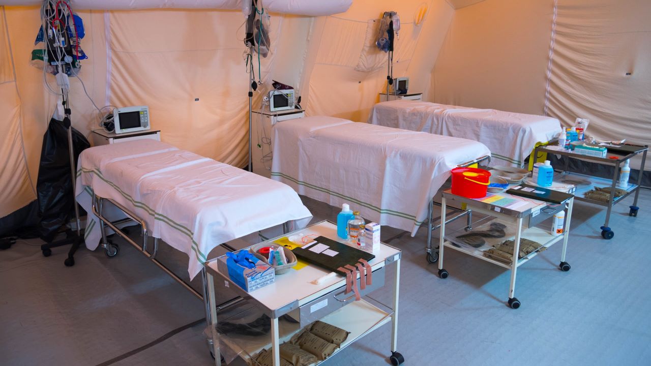 Empty beds lined up in a temporary hospital tent