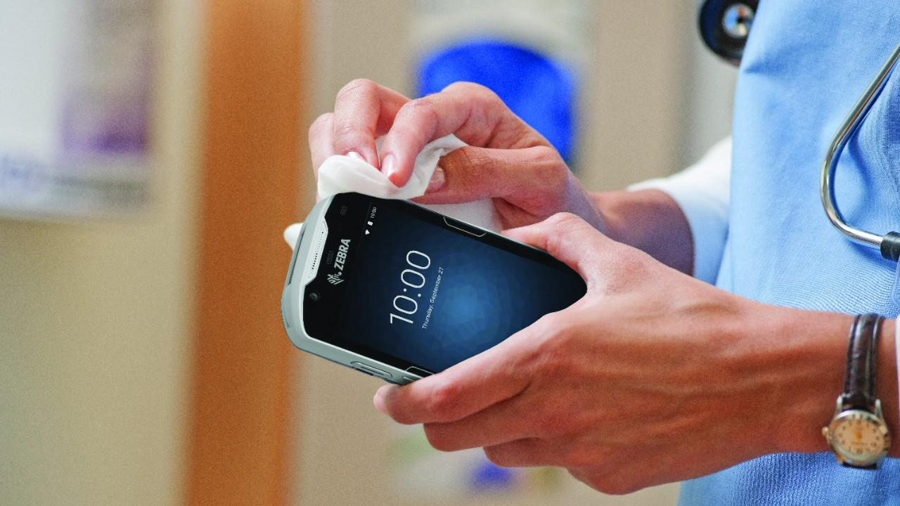 A healthcare provider disinfects a Zebra clinical smartphone