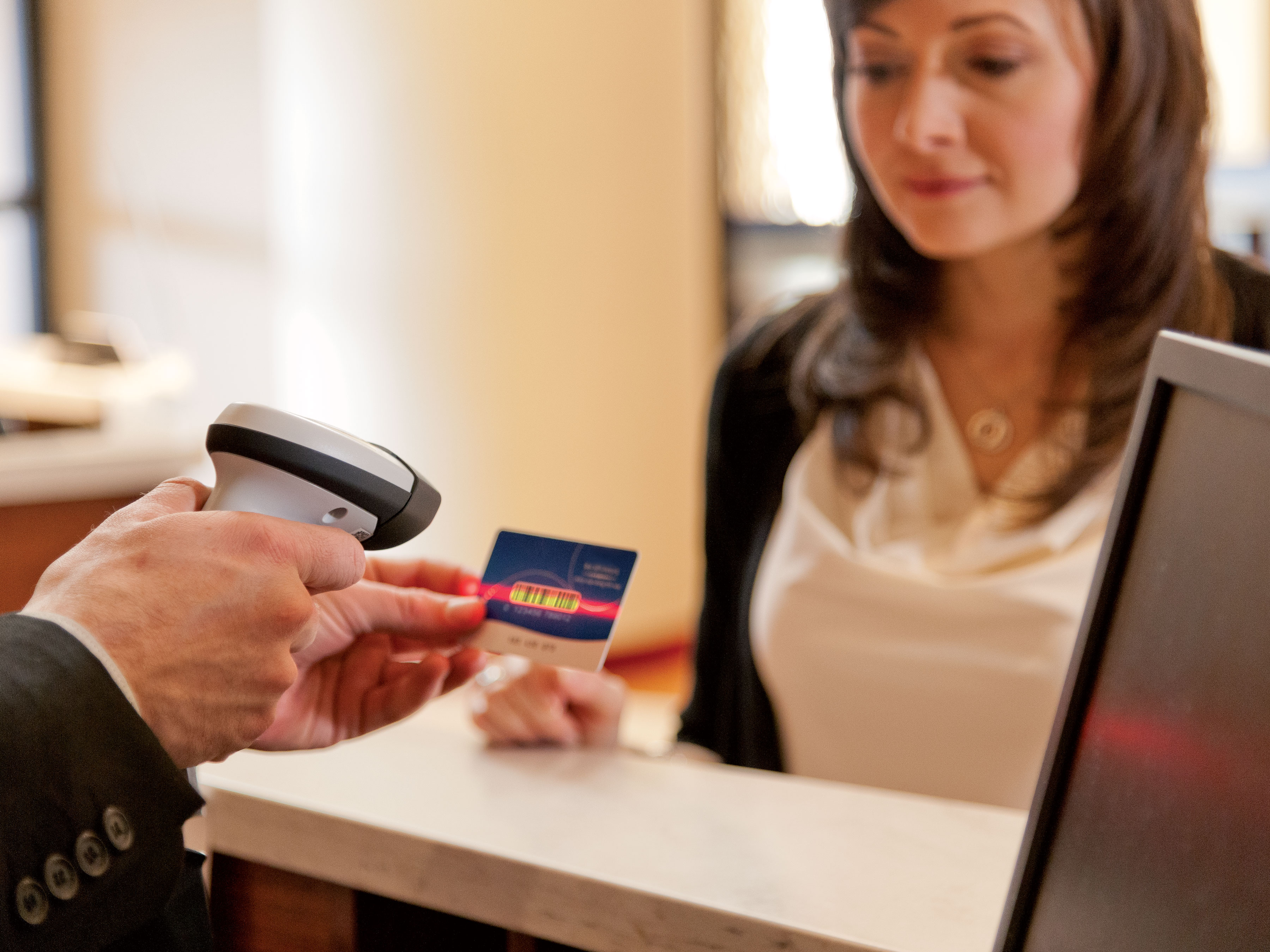 Hotel employee checking in guest with LI2208 scanner and custom printed card