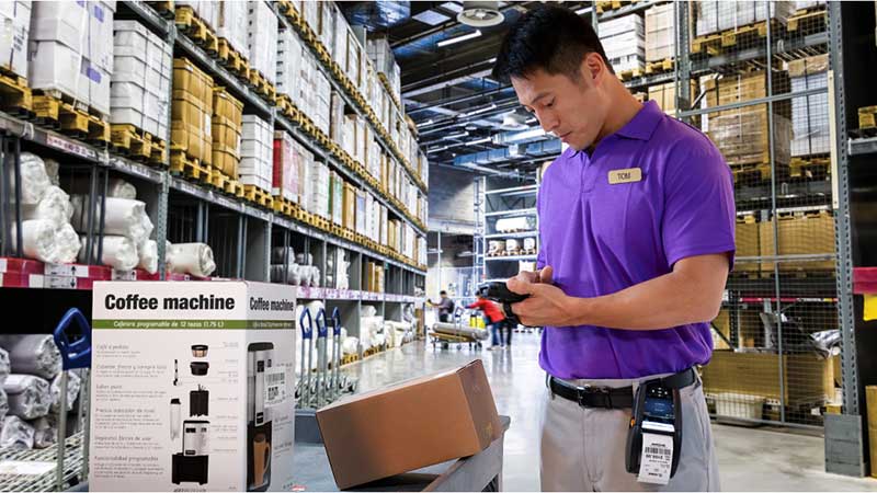 A male warehouse worker uses mobile computers to pick the right products and fulfill an order.