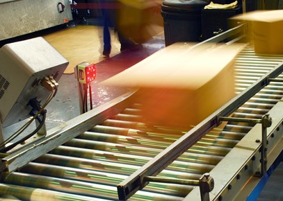 Parcels on a conveyor belt being scanned by fixed scanner using machine vision.