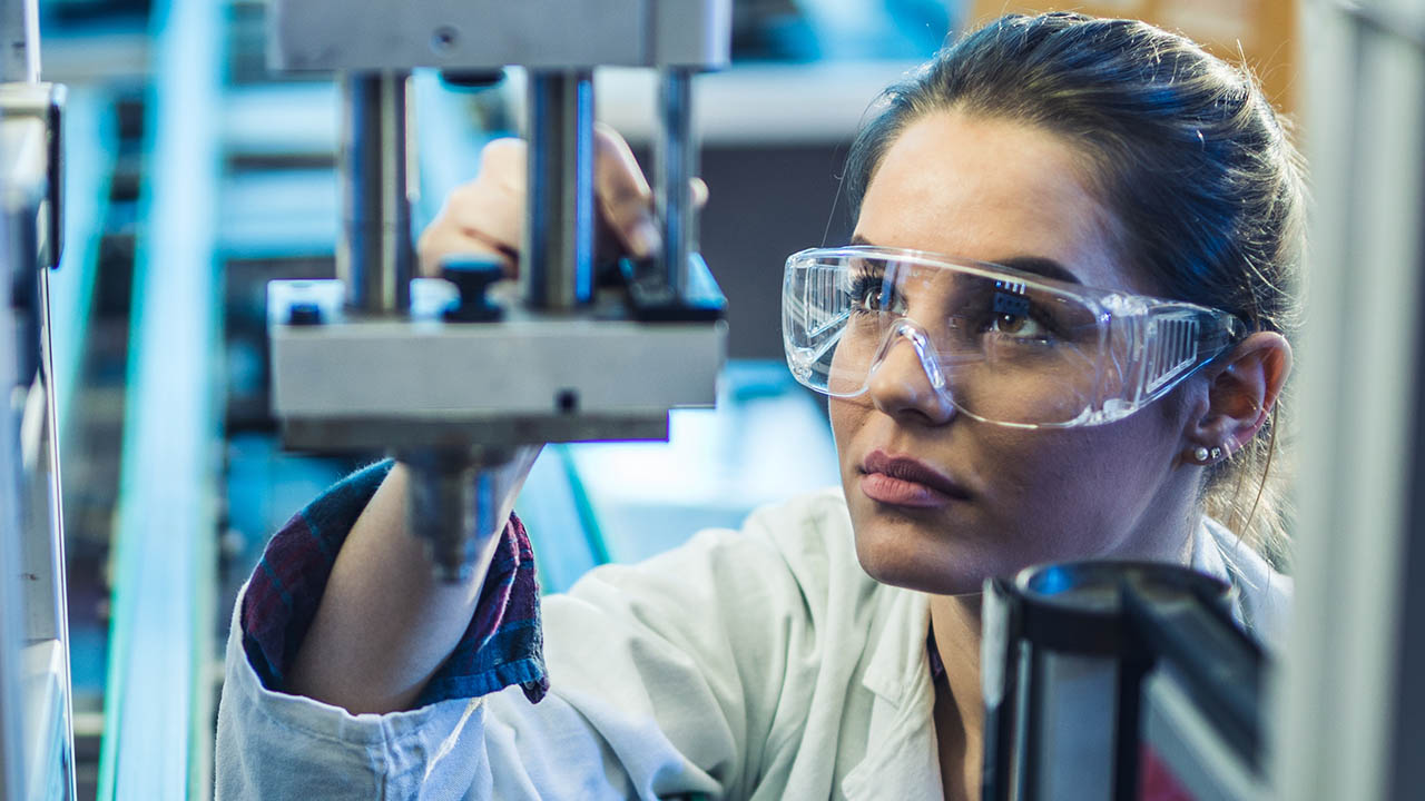 Quality control worker analyzing machine part on a manufacturing machine.