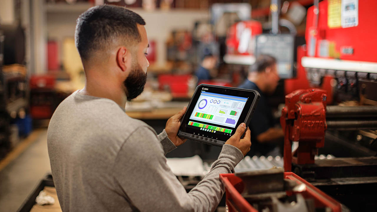 A manufacturing line inspector reviews a dashboad on his Zebra rugged tablet