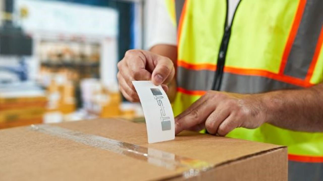 A manufacturing worker applies an RFID label to a box before it is transferred to the loading dock for shipment.