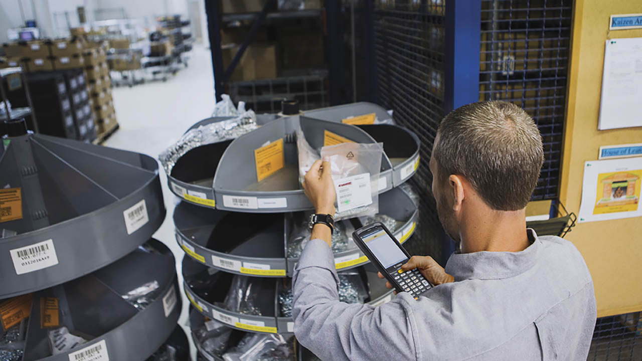 A warehouse workers uses a Zebra MC2XXX mobile computer to scan inventory barcodes.