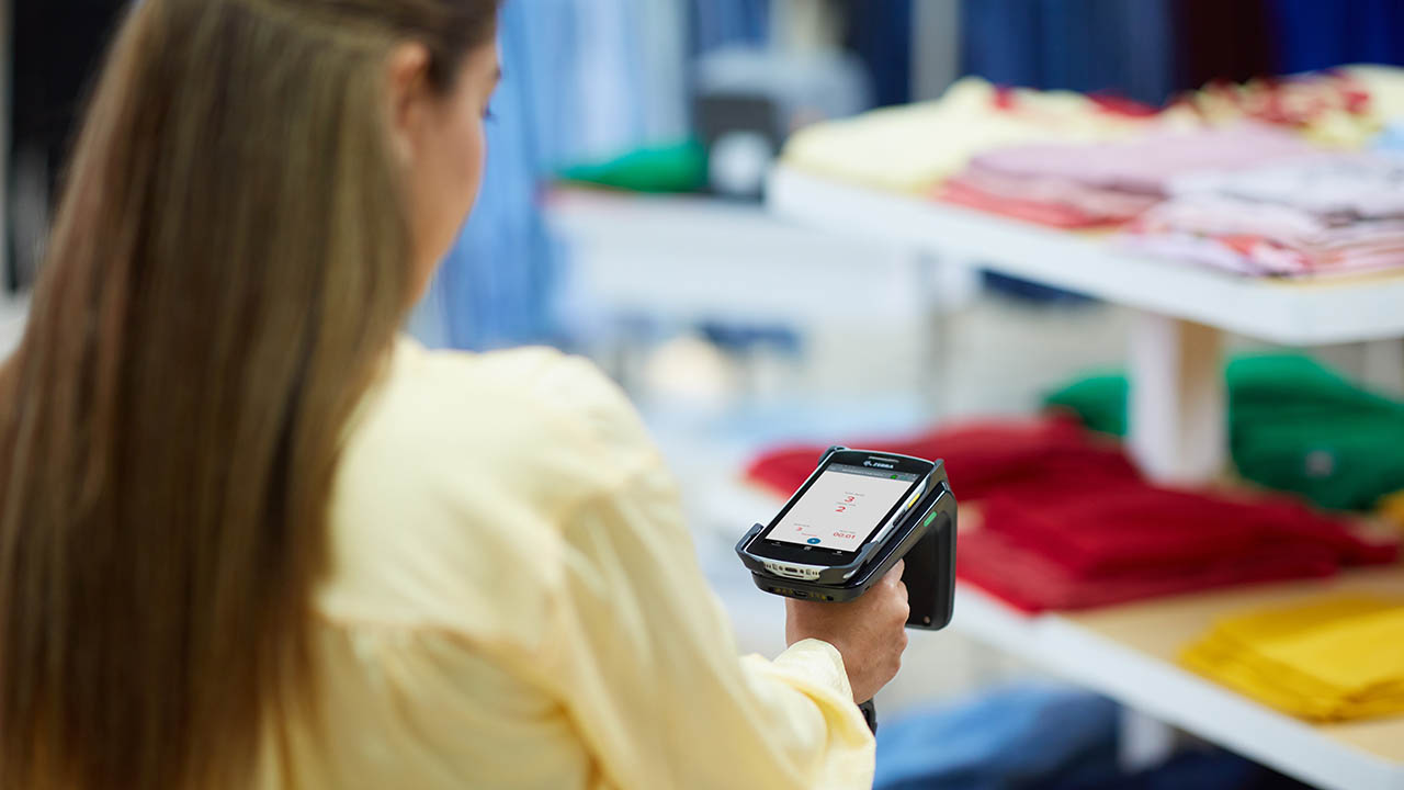 A retail associate uses a Zebra RFD40 handheld RFID sled to read tags on clothing