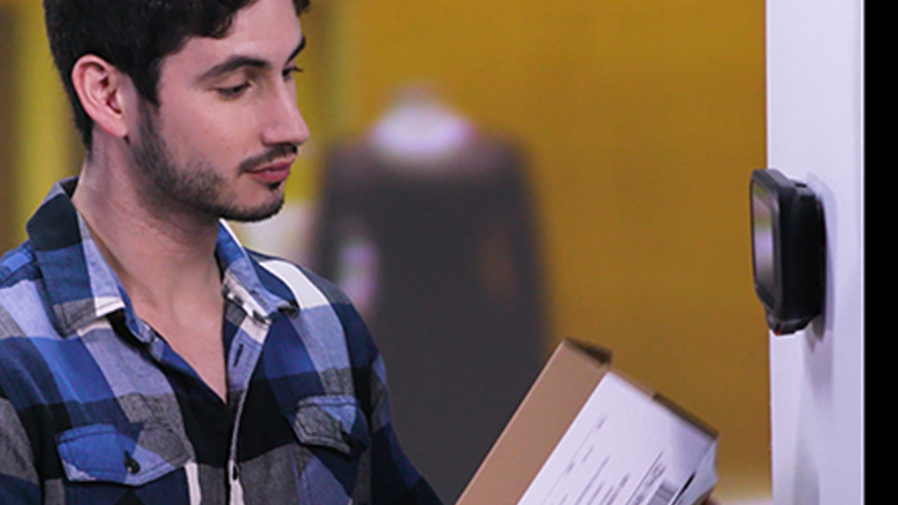 A male shopper scans a box's barcode at a kiosk in a retail store 