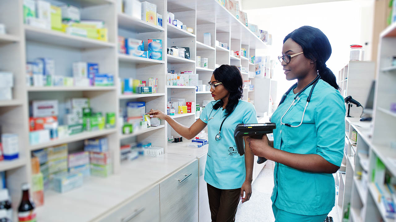 Two clinicians look for items in a stockroom using a mobile computer with RFID sled attached.