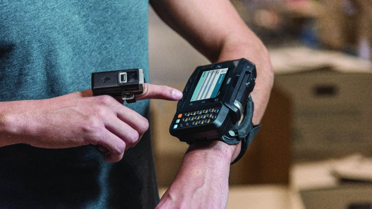 A distribution center worker looks at the next task on his wrist-worn mobile computer.