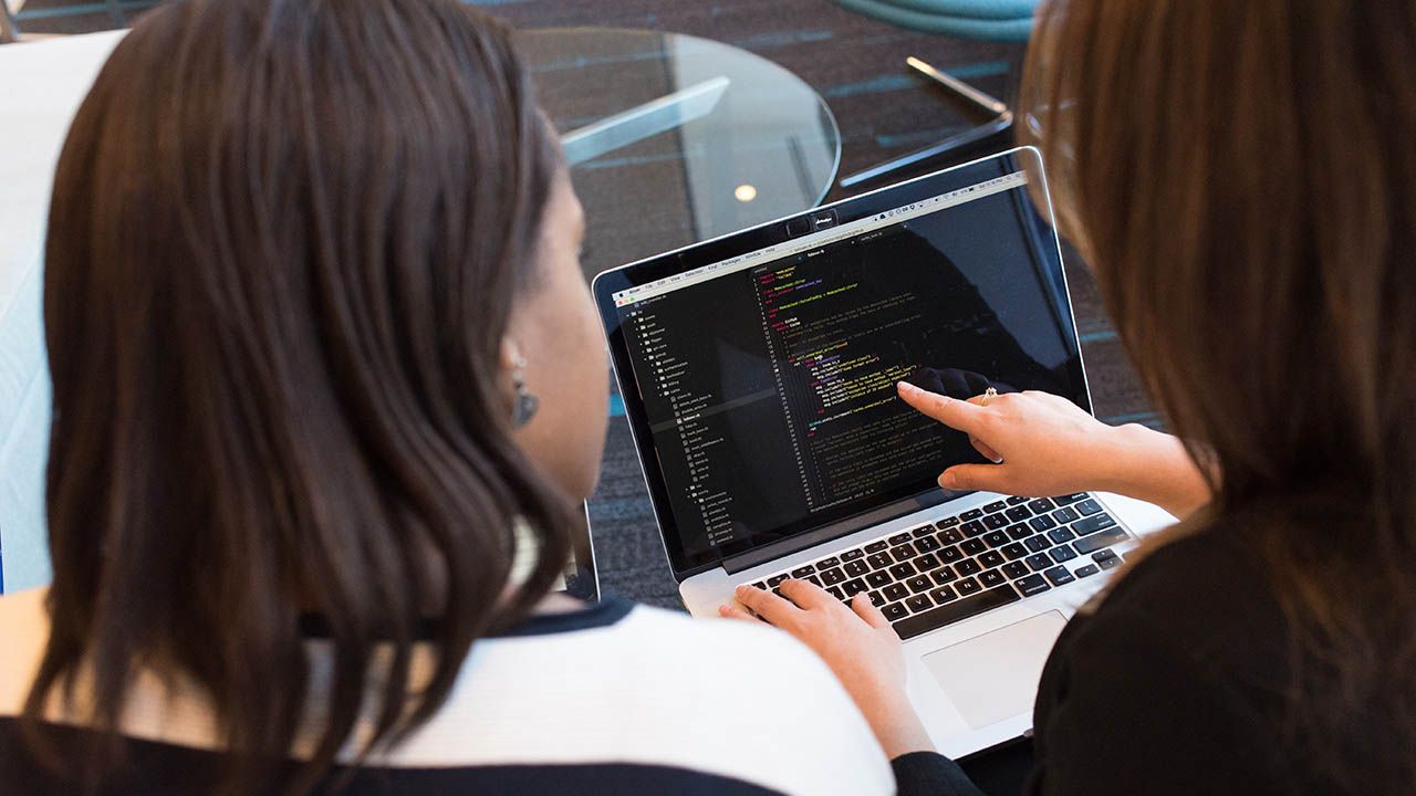 Two women review code on a laptop