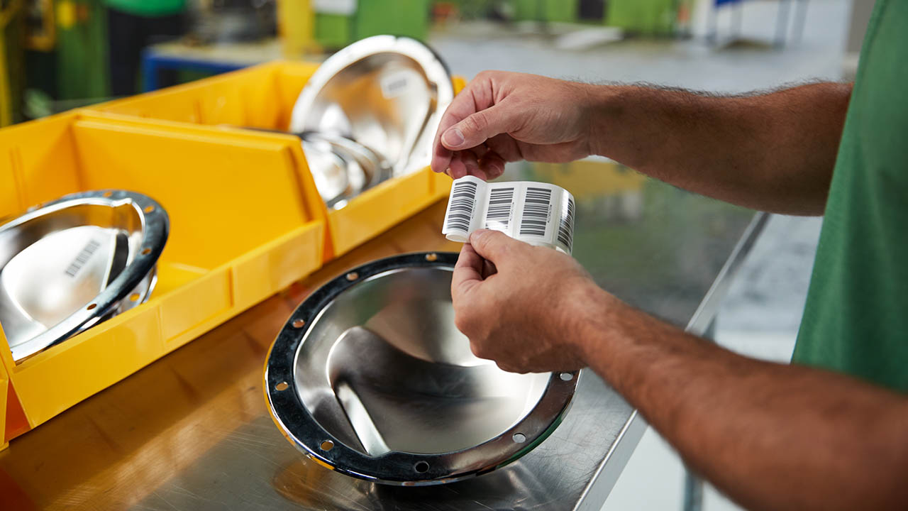 A product ID label is applied to an item in a factory.