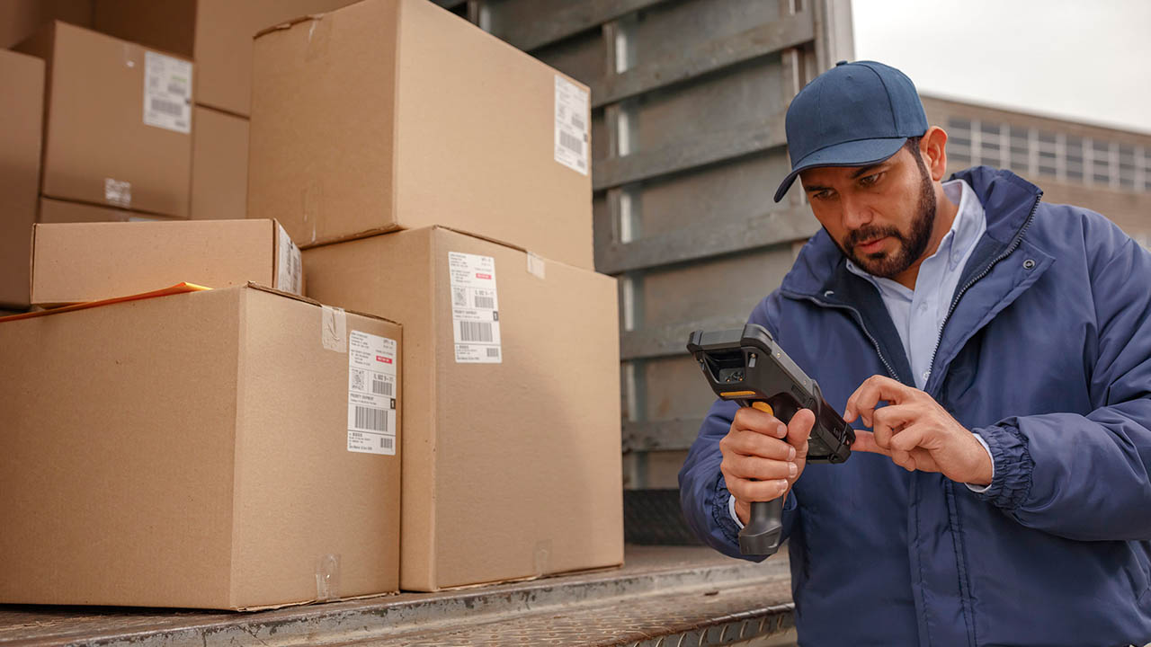 A delivery driver looks at his handheld mobile computer to see which package to deliver nextt