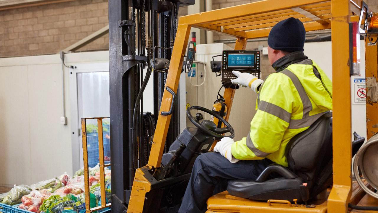 A forklift operator touches the screen of a Zebra VC8300