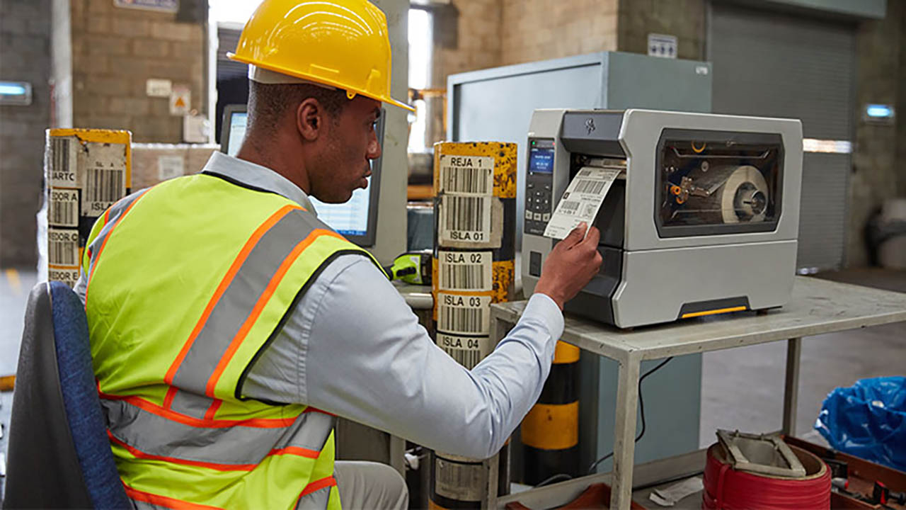 A warehouse worker pulls a label off a Zebra industrial printer.