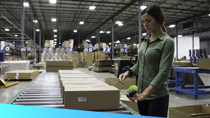 A woman processes a package in a dimly lit warehouse.