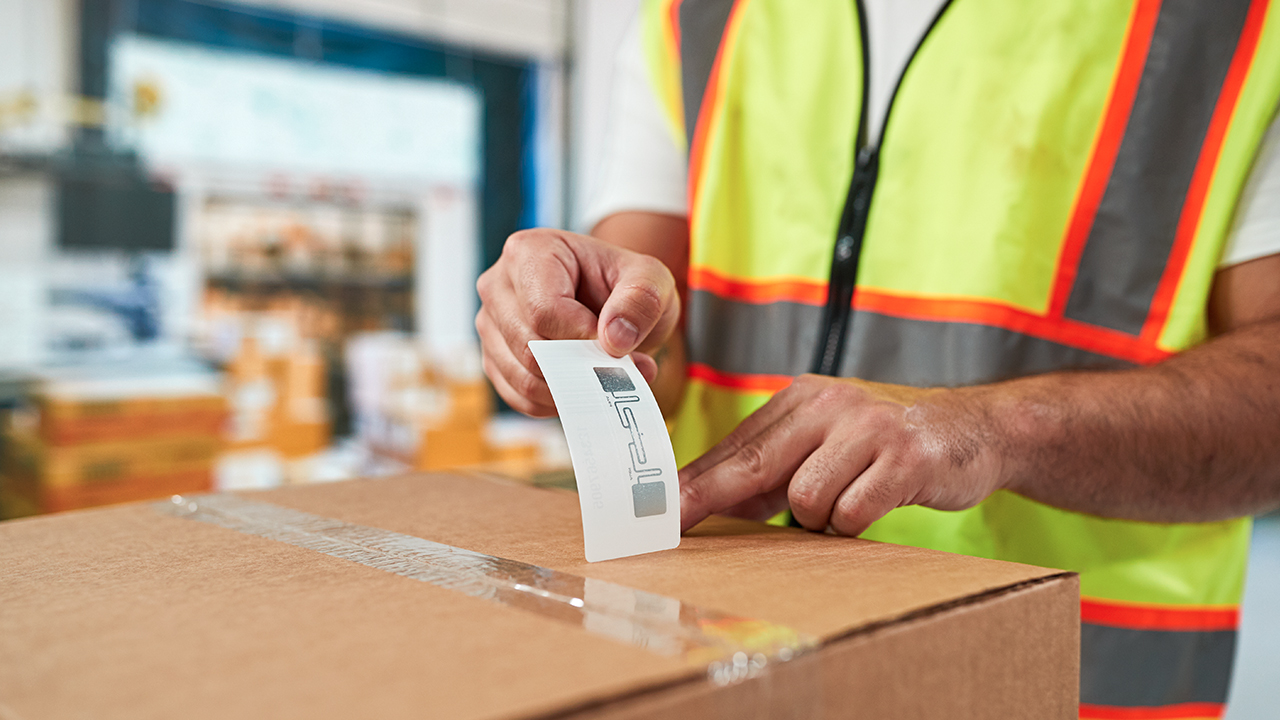 A warehouse worker applies an RFID label to a box