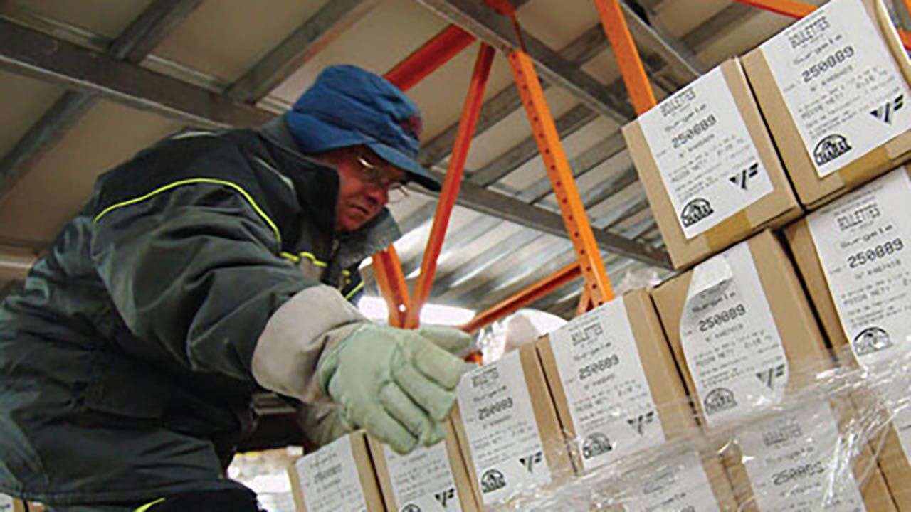 A man removes boxes from a pallet in a cold chain warehouse