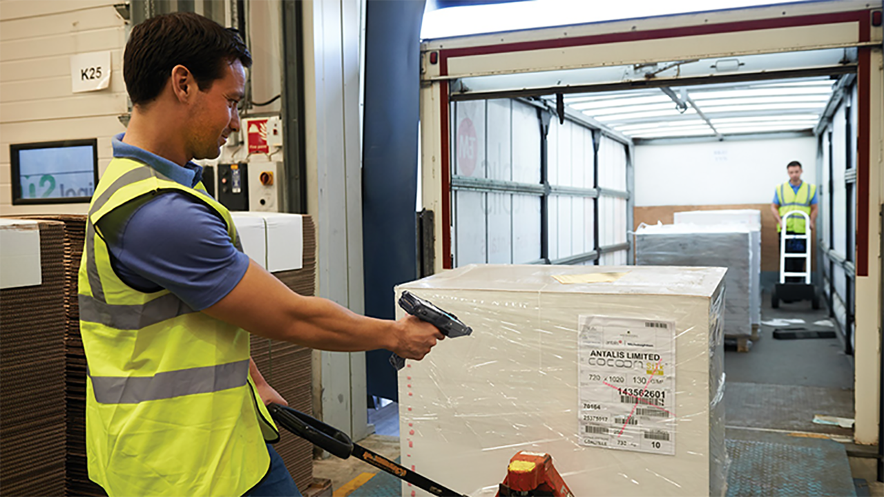 A warehouse worker scans the barcode on a pallet of items after being unloaded from a truck